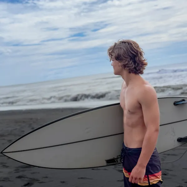 A man holding a surf board looking on the wave