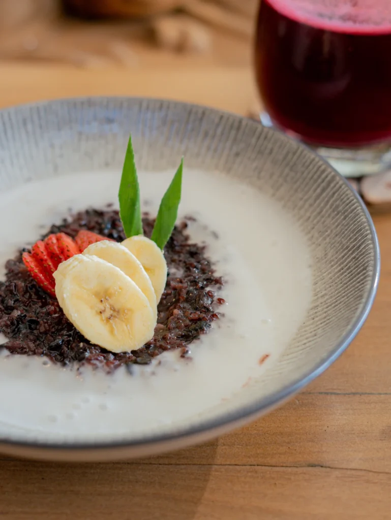 Black sticky rice porridge with coconut milk sauce and banana & strawberry on top