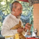 The caretaker is holding a Balinese Hindu religious ceremony